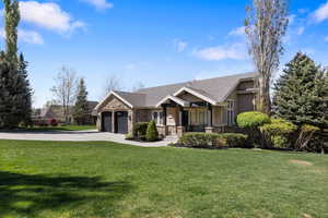 Craftsman house featuring stone siding, a front lawn, driveway, a porch, and an attached garage