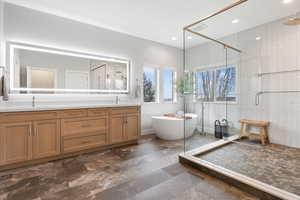 Bathroom with a stall shower, double vanity, a freestanding tub, dark stone finish flooring, and recessed lighting