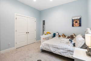 Carpeted bedroom featuring a closet and baseboards