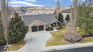 Craftsman-style home with stone siding, a porch, a front lawn, a shingled roof, and an attached garage