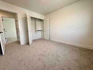Unfurnished bedroom with a closet and light carpet