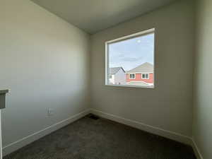 Unfurnished room with dark carpet and baseboards