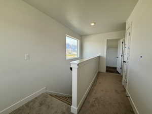 Corridor with an upstairs landing and dark colored carpet