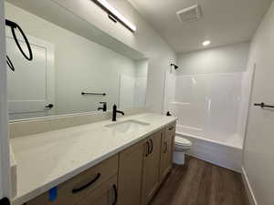 Bathroom with vanity, dark wood-style floors, and  shower combination