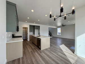 Kitchen with open floor plan, a kitchen island with sink, dark wood finished floors, range with gas cooktop, and decorative backsplash