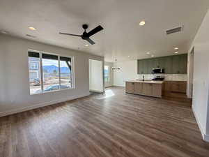 Kitchen with open floor plan, light countertops, a mountain view, a center island with sink, and hanging lights