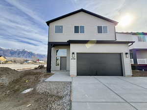 Traditional-style house featuring a garage, concrete driveway, and a mountain view