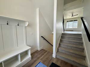 Stairs with wood finished floors and a ceiling fan