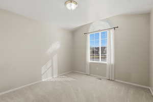 Spare room featuring baseboards and light colored carpet