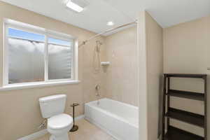 Full bath with shower / tub combination, a textured ceiling, and light tile patterned floors