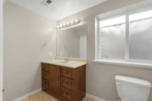 Bathroom with vanity, a textured ceiling, and light tile patterned flooring