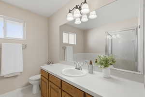 Bathroom with vanity, light tile patterned floors, suspended lighting, and a stall shower