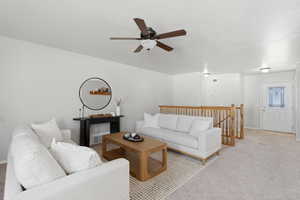 Carpeted living area with ceiling fan and baseboards