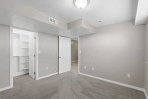 Unfurnished bedroom with a walk in closet and light colored carpet