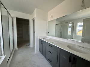 Bathroom with double vanity, a walk in closet, a stall shower, light marble finish floors, and a garden tub