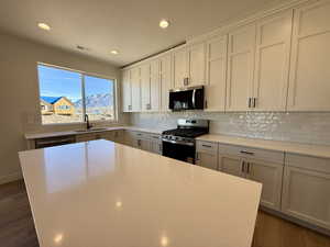 Kitchen with stainless steel appliances, backsplash, light stone counters, recessed lighting, and a center island