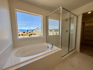 Full bathroom featuring a bath, a walk in closet, a stall shower, and light marble finish floors