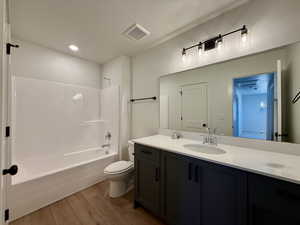 Full bath with light wood finished floors, vanity, bathing tub / shower combination, and recessed lighting
