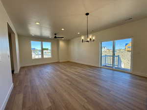Unfurnished dining area with light wood-style flooring, a chandelier, and ceiling fan