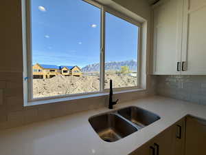 Kitchen featuring light stone countertops, white cabinets, a mountain view, and decorative backsplash