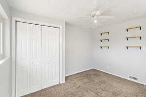 Unfurnished bedroom featuring carpet flooring, a closet, ceiling fan, and a textured ceiling