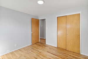 Unfurnished bedroom featuring light wood-type flooring and a closet