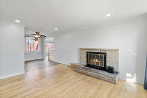Unfurnished living room with ceiling fan, light wood-type flooring, recessed lighting, a glass covered fireplace, and ornamental molding