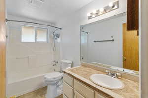 Bathroom with vanity, bathing tub / shower combination, light tile patterned floors, and a textured ceiling