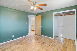 Unfurnished bedroom with light wood-style flooring, ceiling fan, and a closet