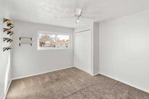 Unfurnished bedroom featuring carpet, a ceiling fan, a closet, and a textured ceiling
