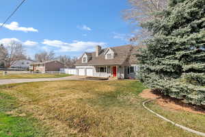Cape cod home featuring a porch, concrete driveway, a garage, and a chimney