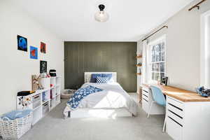 Bedroom featuring an accent wall, wood walls, and carpet flooring
