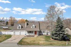 Cape cod house featuring a porch, driveway, a chimney, and a mountain view