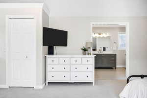 Bedroom with light colored carpet and connected bathroom