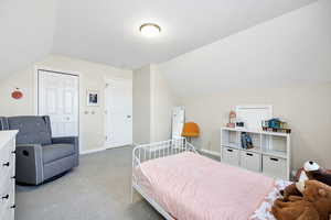 Bedroom featuring light carpet, vaulted ceiling, and a closet