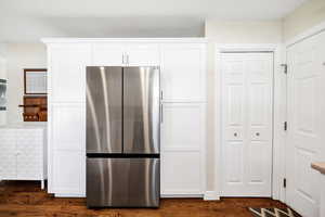 Kitchen featuring freestanding refrigerator, white cabinetry, and dark wood-type flooring
