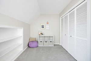 Bedroom featuring light colored carpet, a closet, and vaulted ceiling