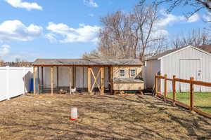 Rear view of property featuring an outbuilding, a fenced backyard, exterior structure, and roof with shingles