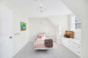 Bedroom with light colored carpet and hanging lights
