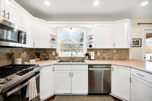 Kitchen with stainless steel appliances, open shelves, white cabinets, and recessed lighting