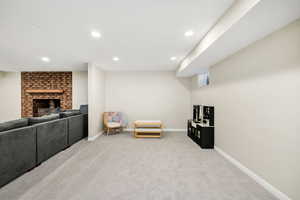 Living area with light carpet, recessed lighting, and a fireplace
