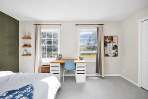 Bedroom with multiple windows, light colored carpet, and a desk