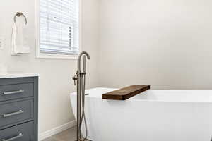 Bathroom featuring vanity, a freestanding tub, and light wood finished floors