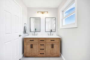 Full bathroom with double vanity and light tile patterned floors
