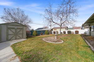 Fenced backyard featuring a storage unit