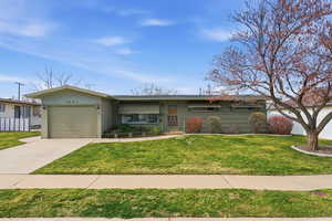 Ranch-style house featuring a garage, driveway, and a front yard