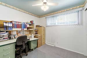 Home office featuring ceiling fan, dark carpet, and a baseboard radiator