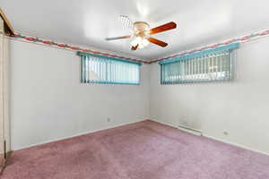 Carpeted empty room featuring ceiling fan and baseboards