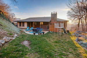 Back of house at dusk with a chimney and a patio