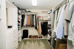 Walk in closet with light colored carpet